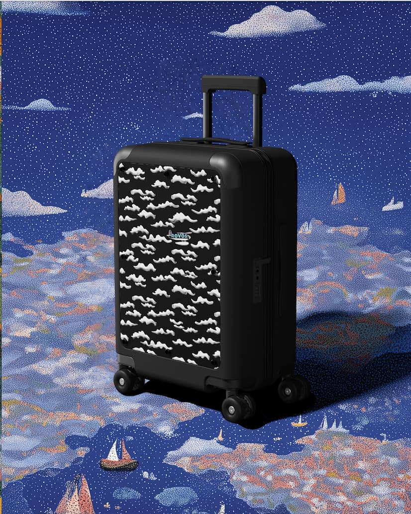 Black designer carry-on luggage with canvas front panel on concrete surface in natural light
